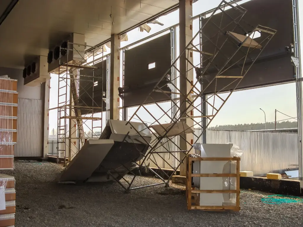 Industrial conveyor machinery above a pile of dark aggregate